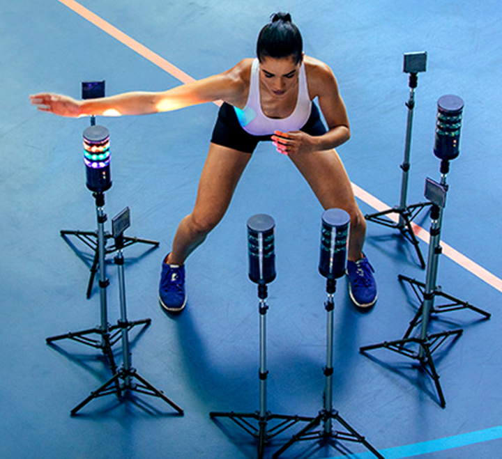 Woman in workout clothing training reaction time using light stands.