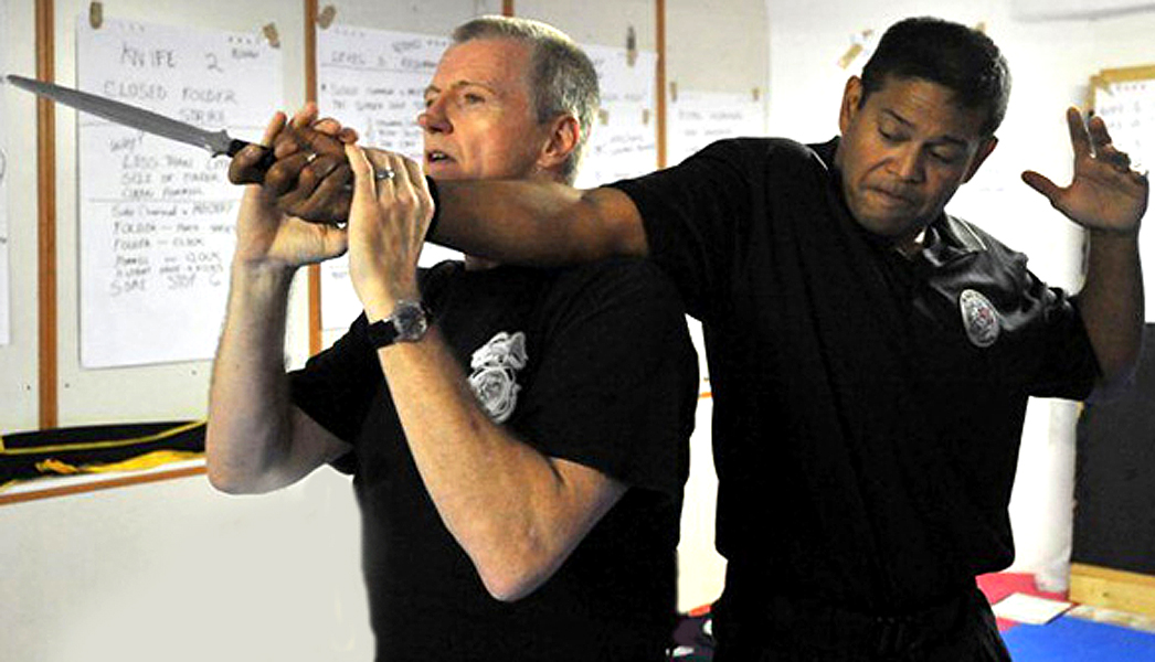 Hock performing an over the shoulder armbar knife release technique.