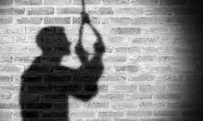 Silhouette of a person climbing a rope against a brick wall, lit from the right side.